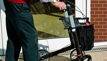 Ein älterer Herr geht mit einem Rollator.