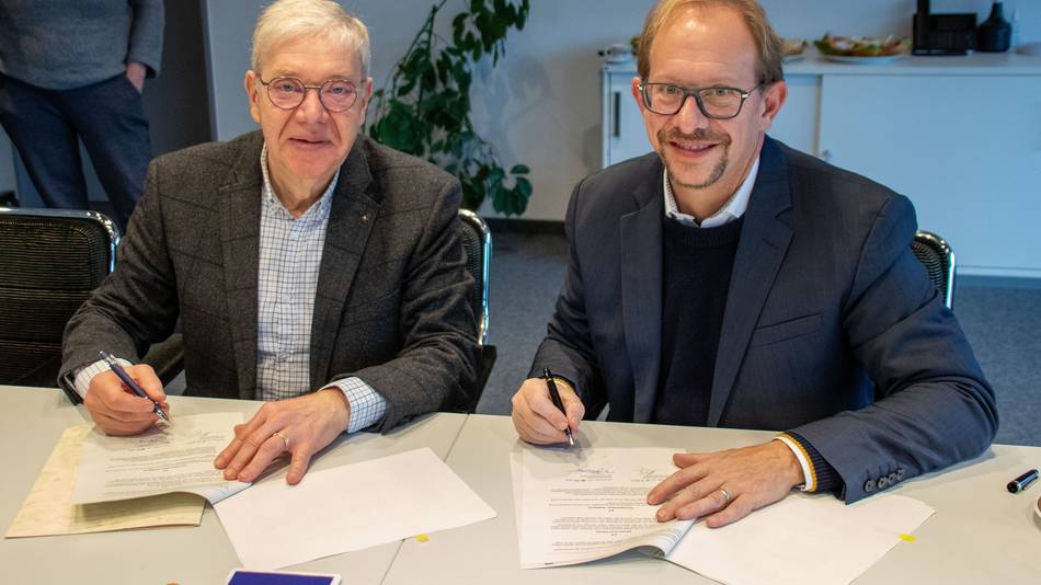 Bürgermeister Hartmut König und Oberbürgermeister Tobias Bergmann sitzen nebeneinander an einem Tisch. Vor ihnen liegen die Verträge, die sie gleich unterzeichnen werden.