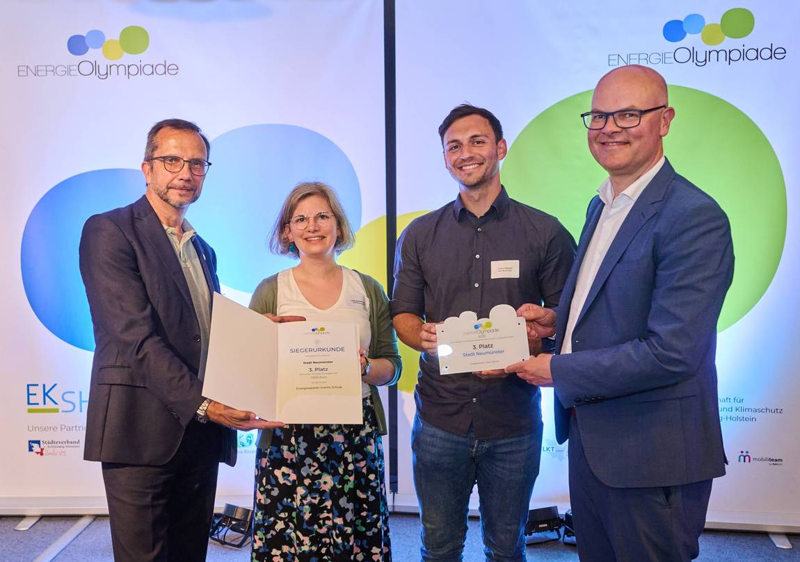 Übergabe der Auszeichnung (von links: Prof. Dr. Frank Osterwald (EKSH-Geschäftsführer), Julia Schirrmacher (Stadt Neumünster), Yunus Göksen (Stadt Neumünster), Tobias Goldschmidt (Umwelt-Minister des Landes Schlewsig-Holstein) ©EKSH/Henrik Matzen Vier Menschen bei der Übergabe der Auszeichnung