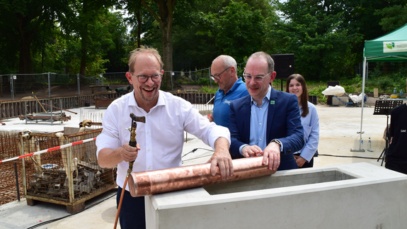 Oberbürgermeister Tobias Bergmann und Schulleiter Jörg Jesper legen gemeinsam eine Zeitkapsel in den ausgehöhlten Grundstein.