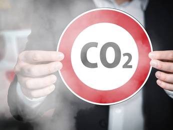 Eine Person, die ein Schild mit der Aufschrift CO2 in den Händen hält. 